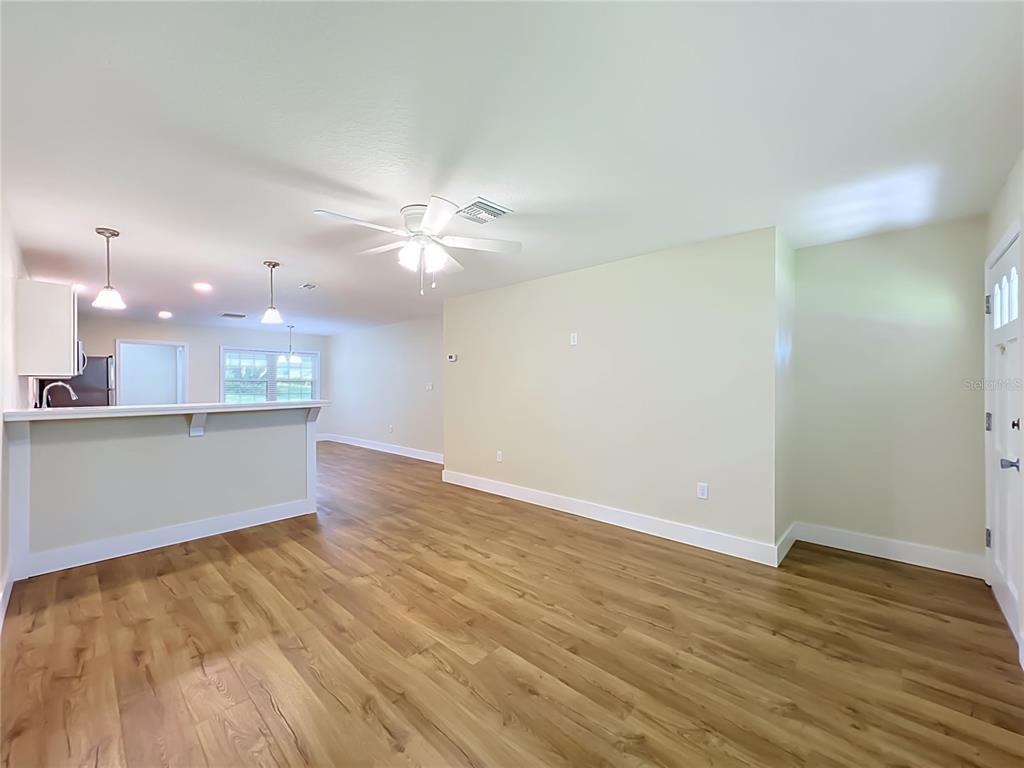 An open-concept living area features light-colored walls, wood-look flooring, and a kitchen breakfast bar — 450 LIBERTY AVENUE UNIT 3, MOUNT DORA, FL