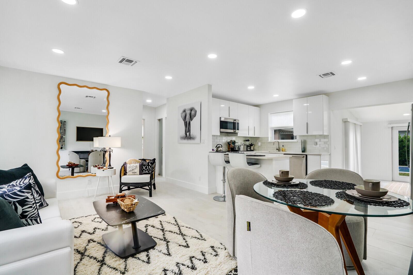 An open-concept living and dining area features white cabinetry, a glass table, and a mirror — 340 Summa Street, West Palm Beach FL 33405, WEST PALM BEACH, FL