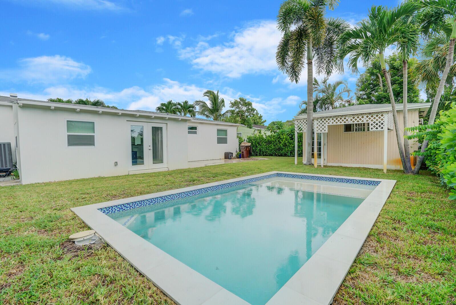 A backyard features a rectangular swimming pool, a white house, and a detached shed — 340 Summa Street, West Palm Beach FL 33405, WEST PALM BEACH, FL