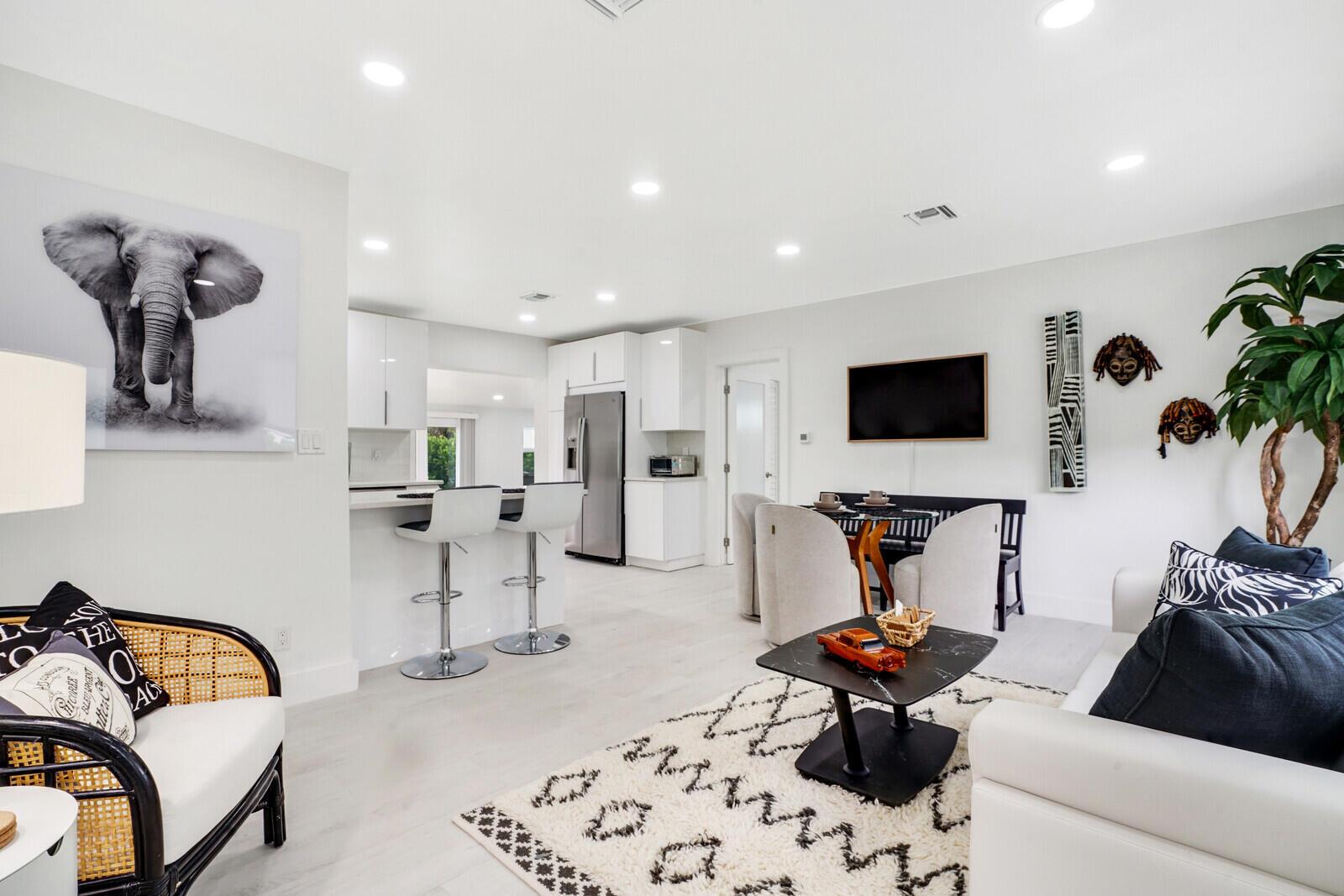 A bright, open-concept living and dining area features white cabinetry, modern furniture, and neutral decor — 340 Summa Street, West Palm Beach FL 33405, WEST PALM BEACH, FL