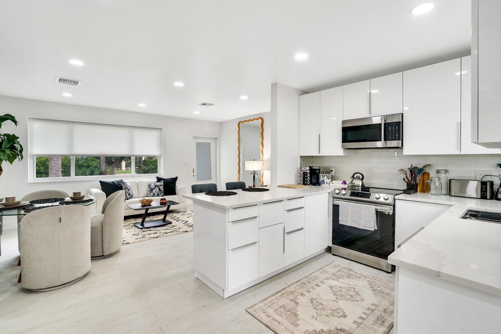 A modern open-concept kitchen and living area featuring white cabinetry, stainless steel appliances, and furniture — 340 Summa Street, West Palm Beach FL 33405, WEST PALM BEACH, FL