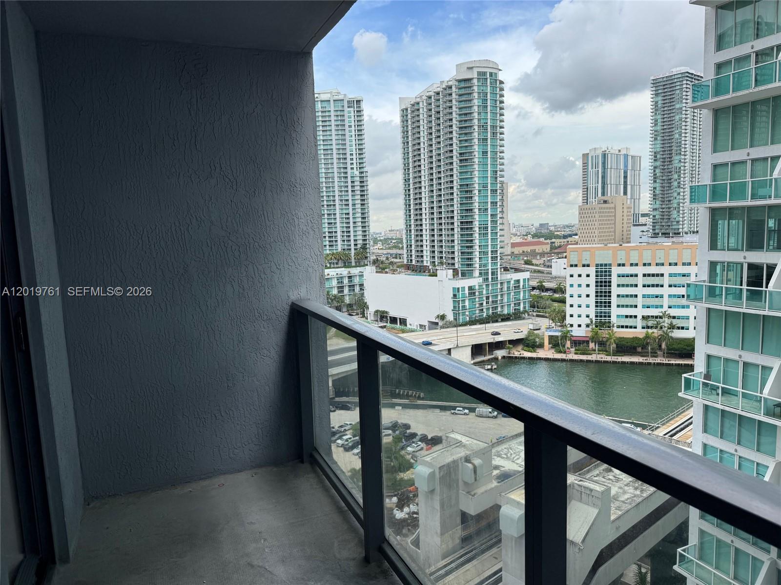 A balcony with a glass railing overlooks a city skyline, a river, and parking lots — 31 SE 6th St # 2004, Miami FL 33131, MIAMI, FL