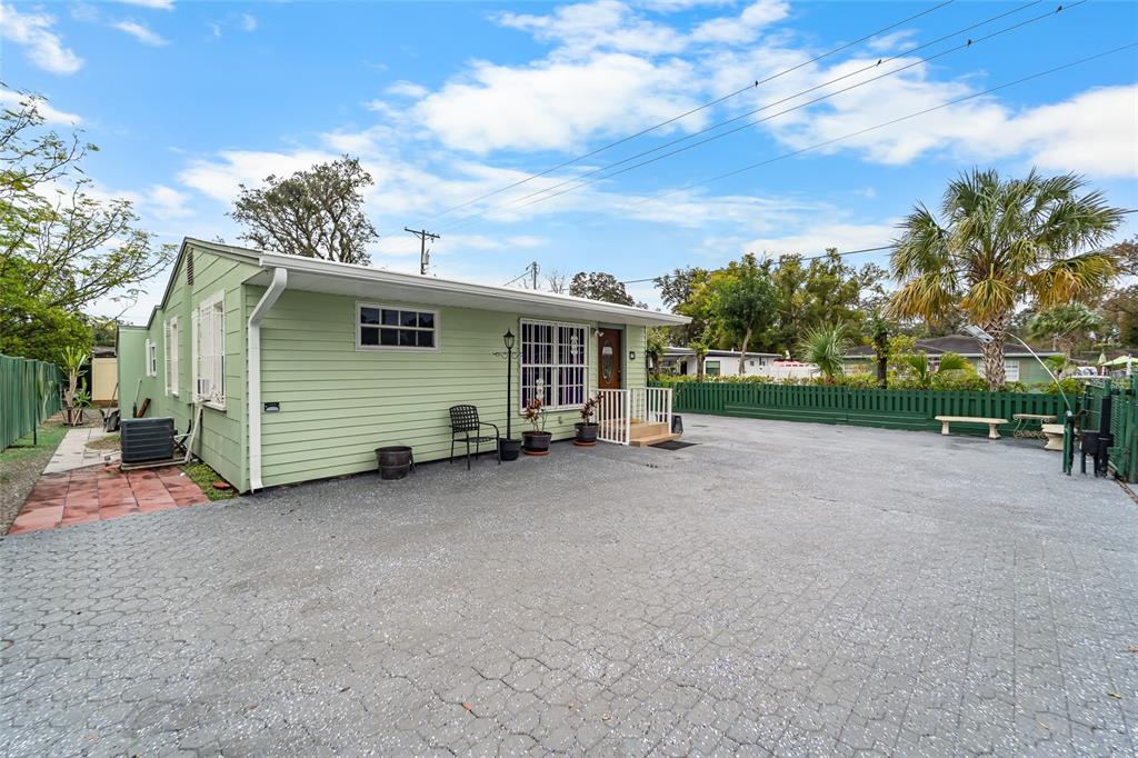 A light green house with a paved driveway and a fenced yard under a blue sky — 10001 N ARDEN AVENUE, TAMPA, FL