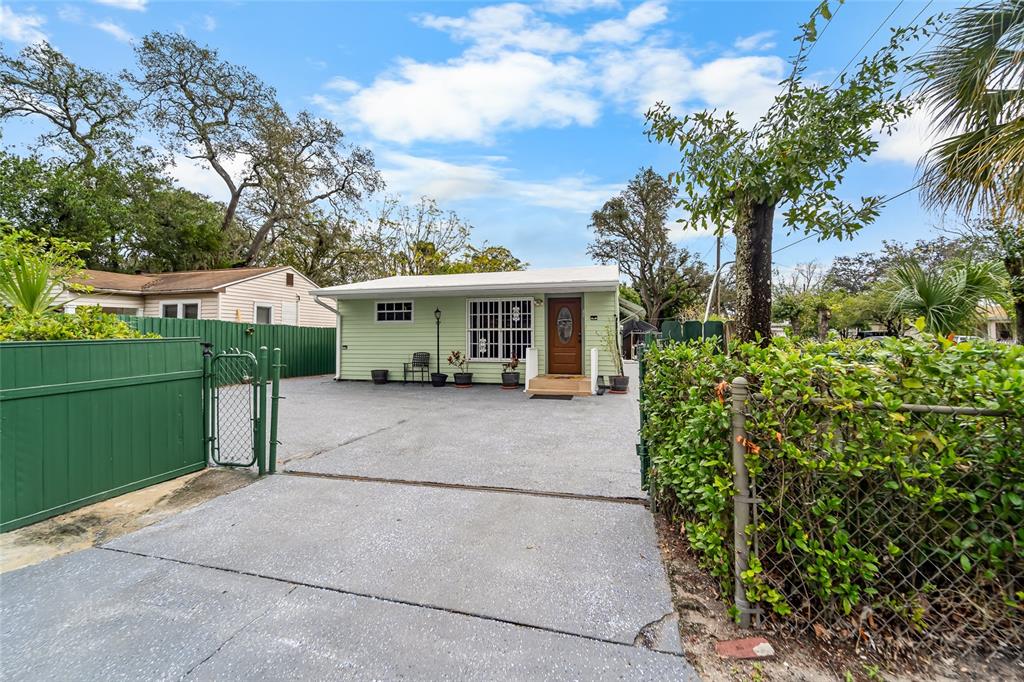 A light green single-story house features a concrete driveway, a front door, and fenced yards — 10001 N ARDEN AVENUE, TAMPA, FL