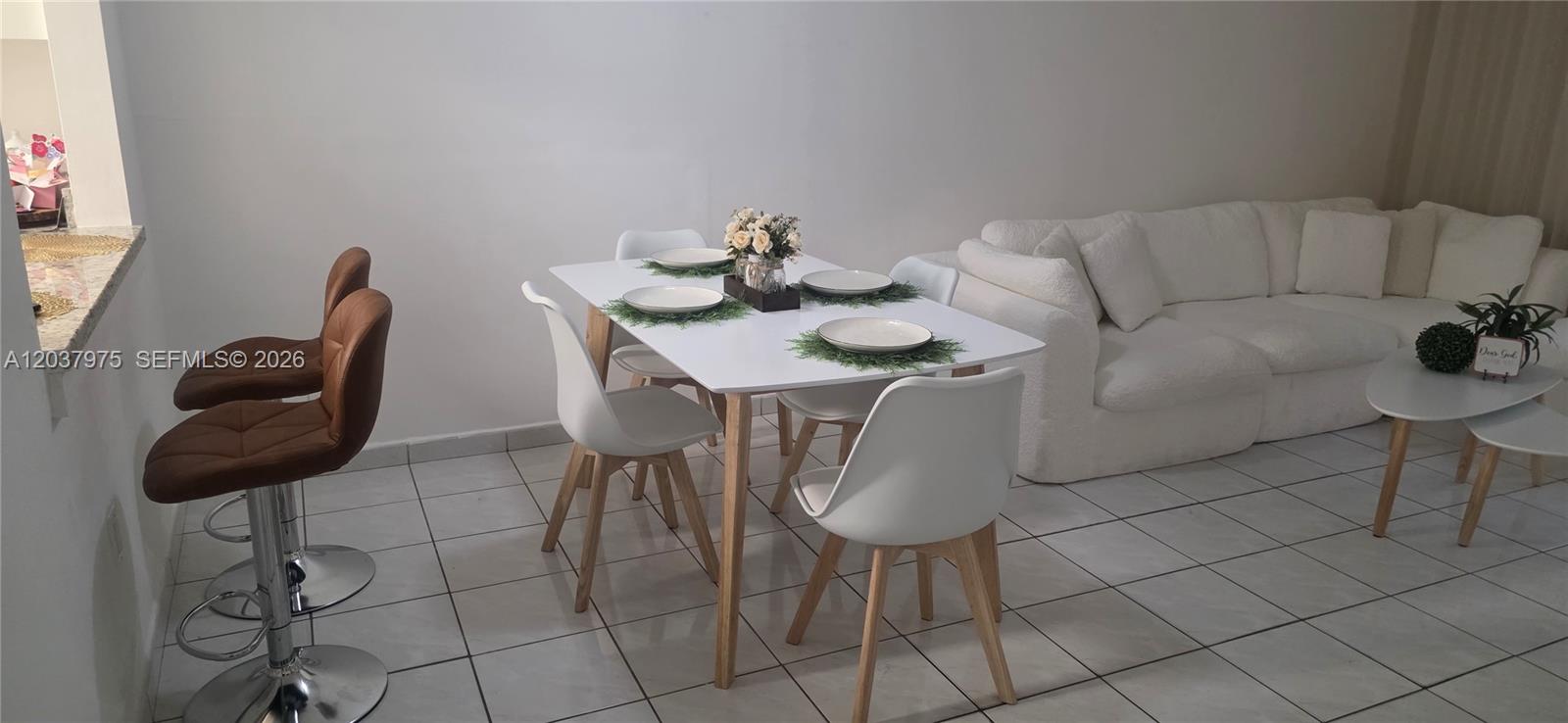 A dining area with a white table and chairs sits next to a white sofa — 10000 NW 80th Ct # 2149, Hialeah Gardens FL 33016, HIALEAH GARDENS, FL