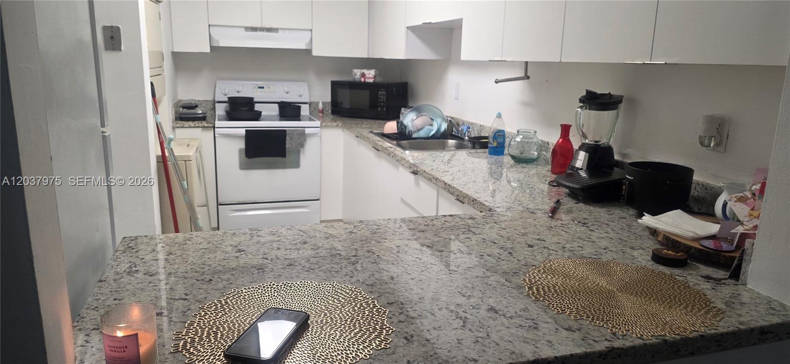 A kitchen features white cabinets, granite countertops, and white appliances — 10000 NW 80th Ct # 2149, Hialeah Gardens FL 33016, HIALEAH GARDENS, FL