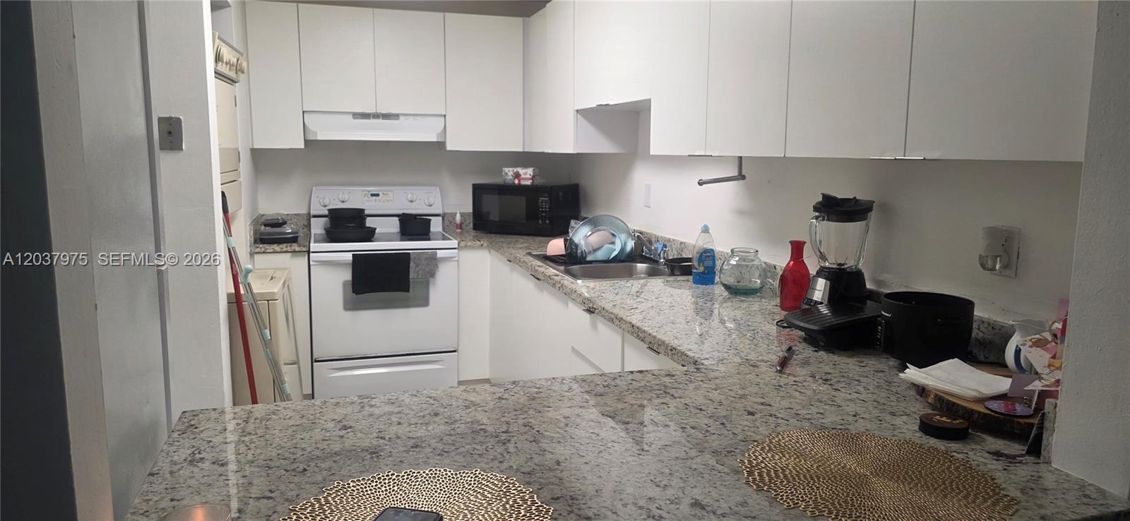 A kitchen features white cabinets, granite countertops, and white appliances — 10000 NW 80th Ct # 2149, Hialeah Gardens FL 33016, HIALEAH GARDENS, FL