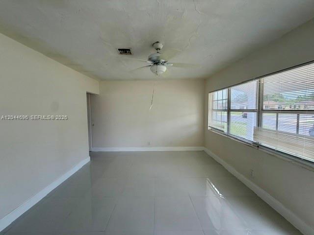 An empty room features light-colored tile flooring, plain walls, and a ceiling fan — 2115 SW 50th Ave, West Park FL 33023, WEST PARK, FL