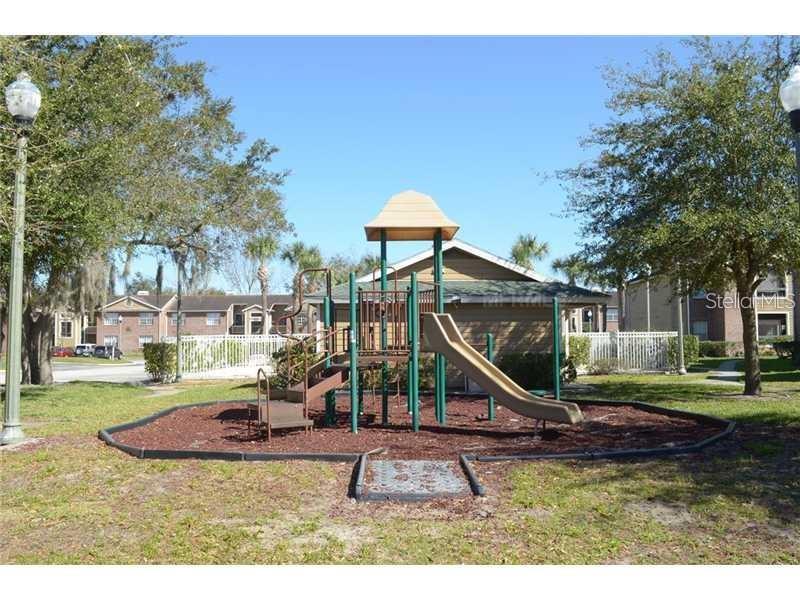 A playground with a slide and climbing structure sits on a mulch bed outdoors — 4367 THORNBRIAR LANE UNIT P104, ORLANDO, FL