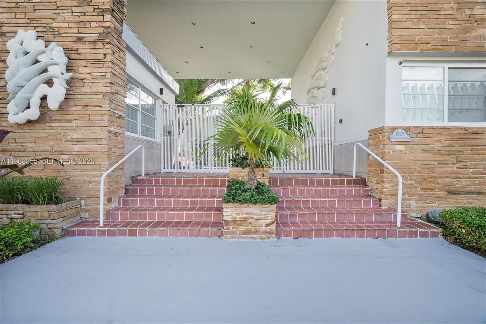 A stone-clad building entrance features red tile steps, a central planter, and a white gate — 1925 Washington Ave # 21, Miami Beach FL 33139, MIAMI BEACH, FL