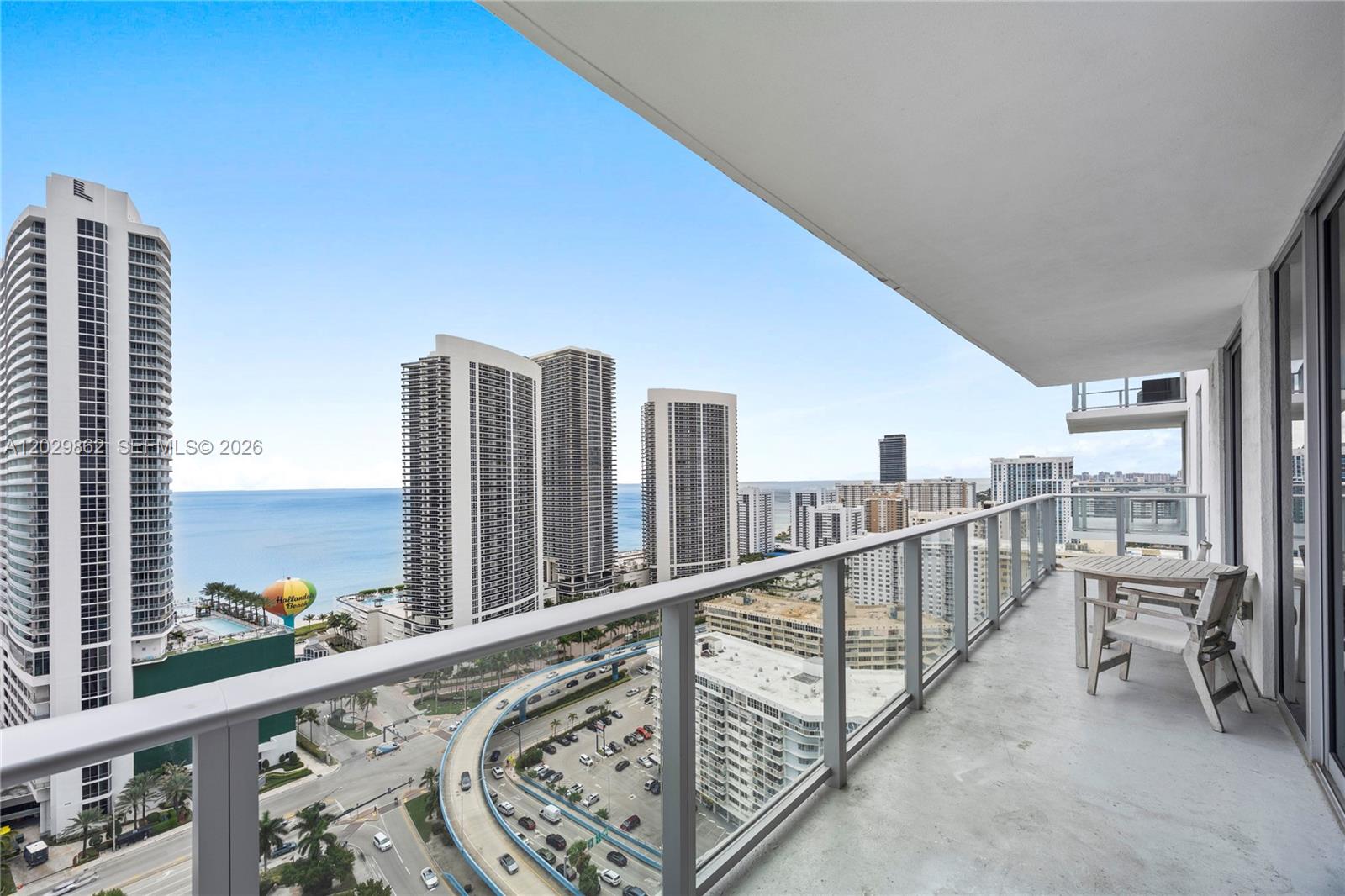 A high-rise balcony overlooks a coastal city with ocean views and a parking structure — 4010 S Ocean Dr # R2307, Hollywood FL 33019, HOLLYWOOD, FL