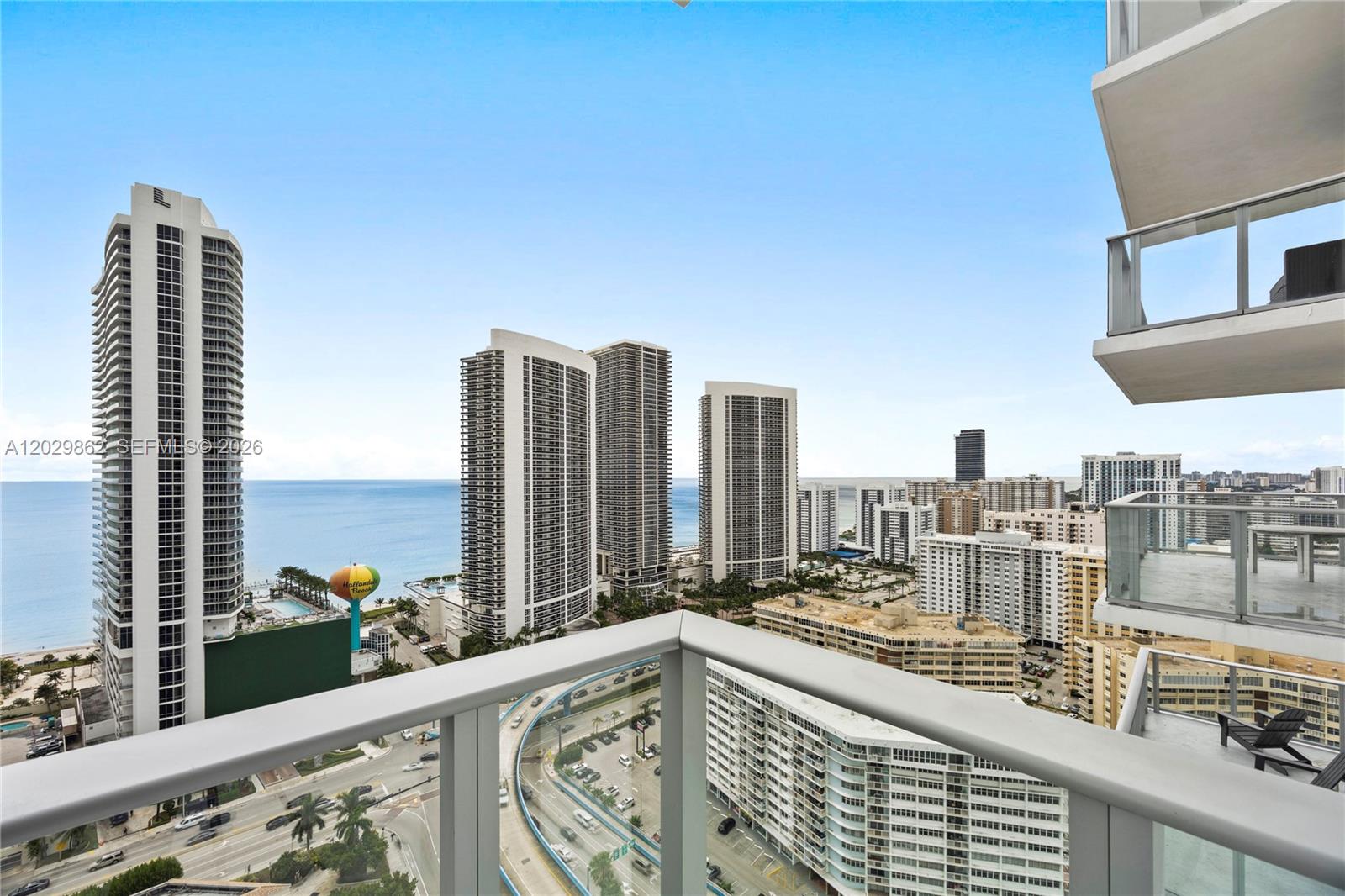 A balcony view overlooks a coastal city with high-rise buildings, a highway, and the ocean — 4010 S Ocean Dr # R2307, Hollywood FL 33019, HOLLYWOOD, FL