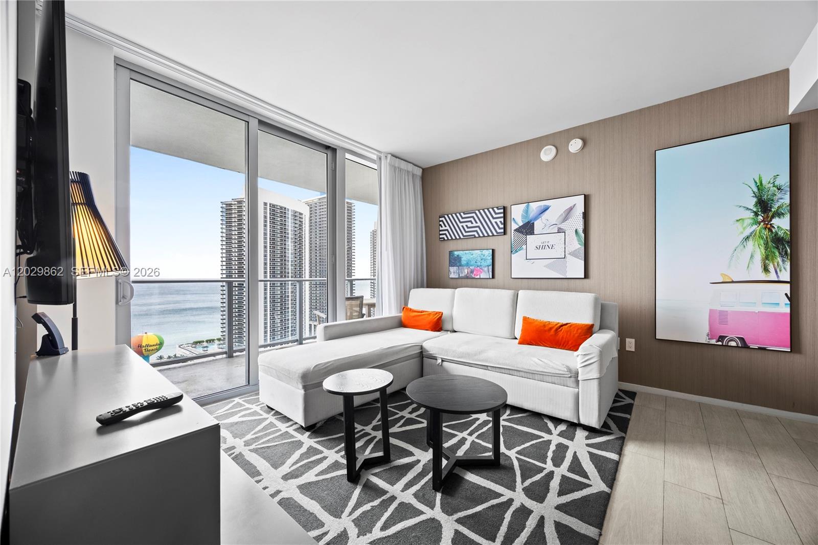 A living room features a white sectional sofa, two round tables, and a balcony view — 4010 S Ocean Dr # R2307, Hollywood FL 33019, HOLLYWOOD, FL