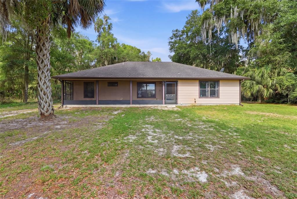The rear exterior of a single-story house features a screened-in porch and tan siding — 173 LITTLE ORANGE LAKE DRIVE, HAWTHORNE, FL