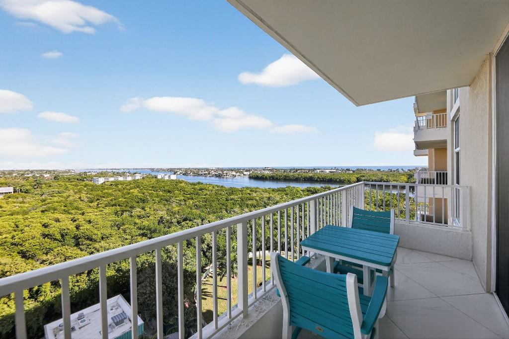 A balcony with teal patio furniture overlooks a dense forest and a distant waterway — 700 E Boynton Beach Boulevard # 1006, Boynton Beach FL 33435, BOYNTON BEACH, FL