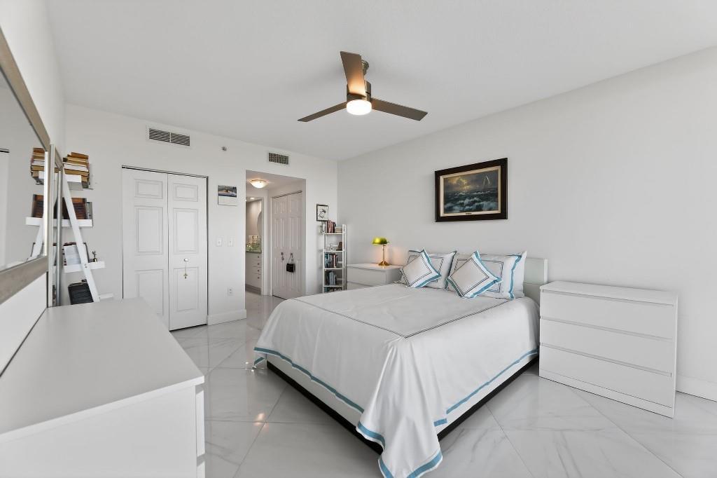 A bright bedroom features a queen bed, white furniture, tile flooring, and a ceiling fan — 700 E Boynton Beach Boulevard # 1006, Boynton Beach FL 33435, BOYNTON BEACH, FL