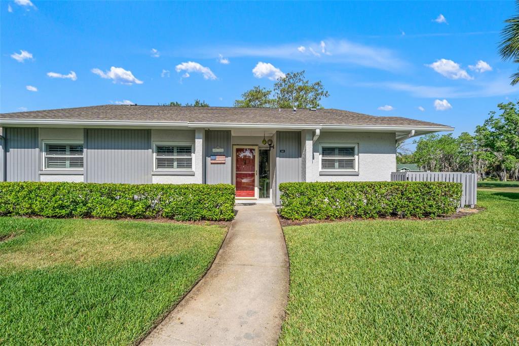 A single-story house with a gray exterior, a red front door, and a manicured hedge — 140 ASHLEY LANE, OLDSMAR, FL