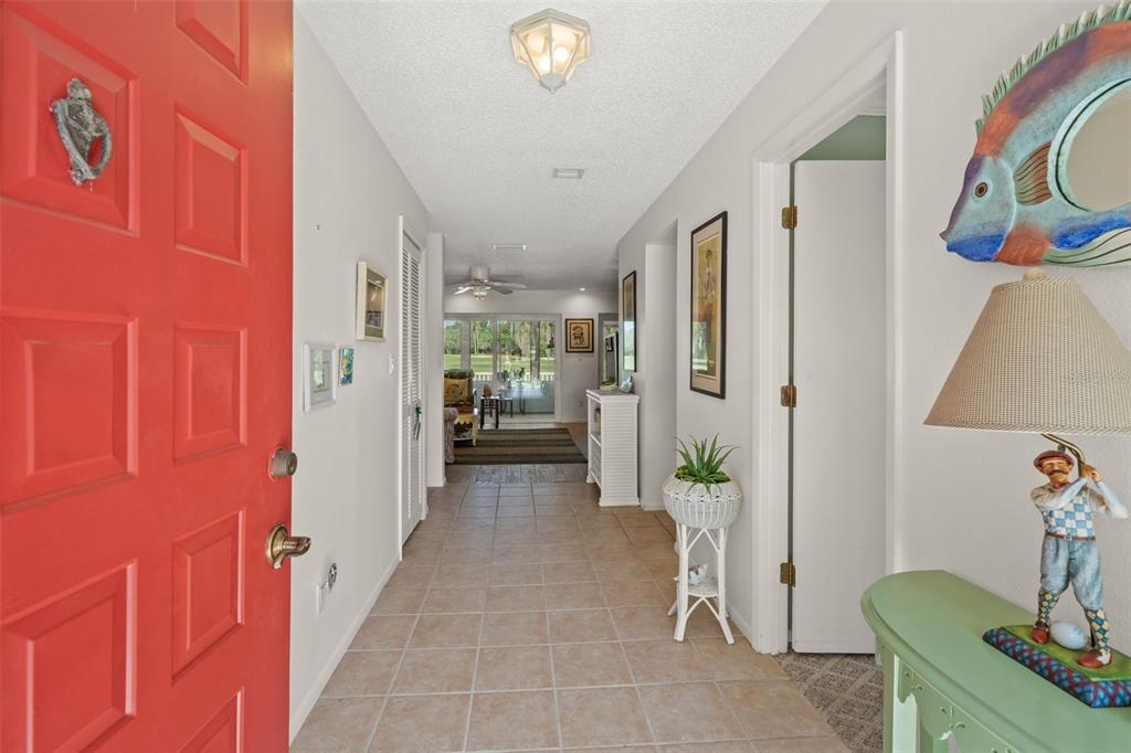A tiled entryway leads from a red front door toward a living area with views — 140 ASHLEY LANE, OLDSMAR, FL