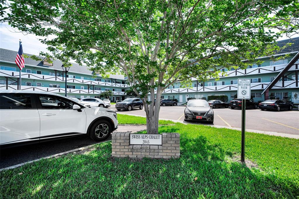 A white car is parked in front of a multi-story building labeled Swiss Alps Chalet — 2043 DENMARK STREET UNIT 39, CLEARWATER, FL