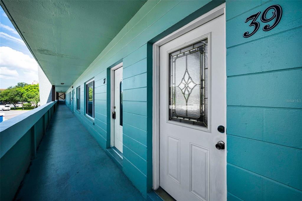 An exterior walkway with teal walls leads to a white door marked with number 39 — 2043 DENMARK STREET UNIT 39, CLEARWATER, FL