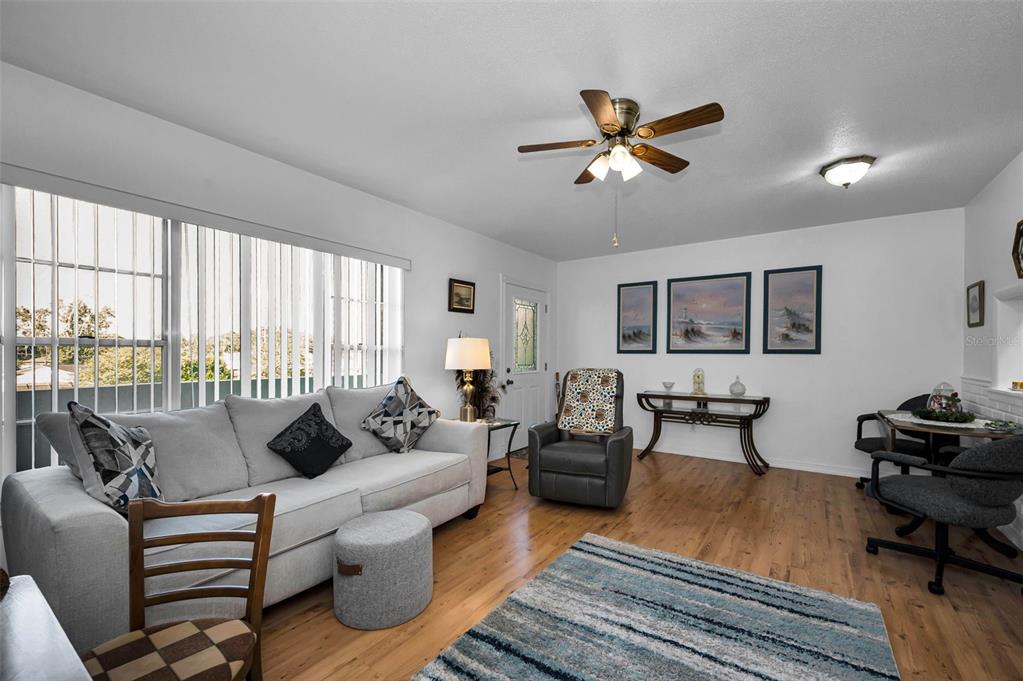 A living room features light wood flooring, a gray sofa, a recliner, and a ceiling fan — 2043 DENMARK STREET UNIT 39, CLEARWATER, FL