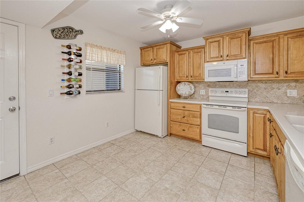 A kitchen with light wood cabinets, white appliances, tile flooring, and a wall-mounted wine rack — 175 KINGS HIGHWAY UNIT 225 (B5), PUNTA GORDA, FL