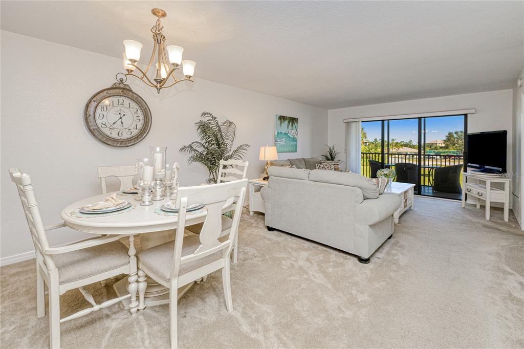 A dining area with a round table and a living room with a balcony view — 175 KINGS HIGHWAY UNIT 225 (B5), PUNTA GORDA, FL