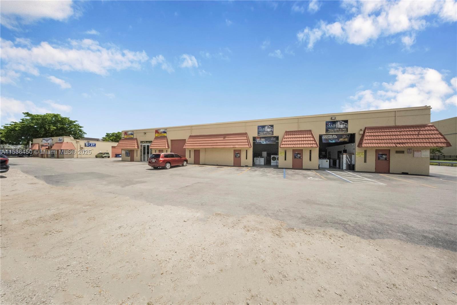 A single-story commercial building with multiple storefronts and a large paved parking lot — 10890 QUAIL ROOST DR, Miami FL 33157, MIAMI, FL