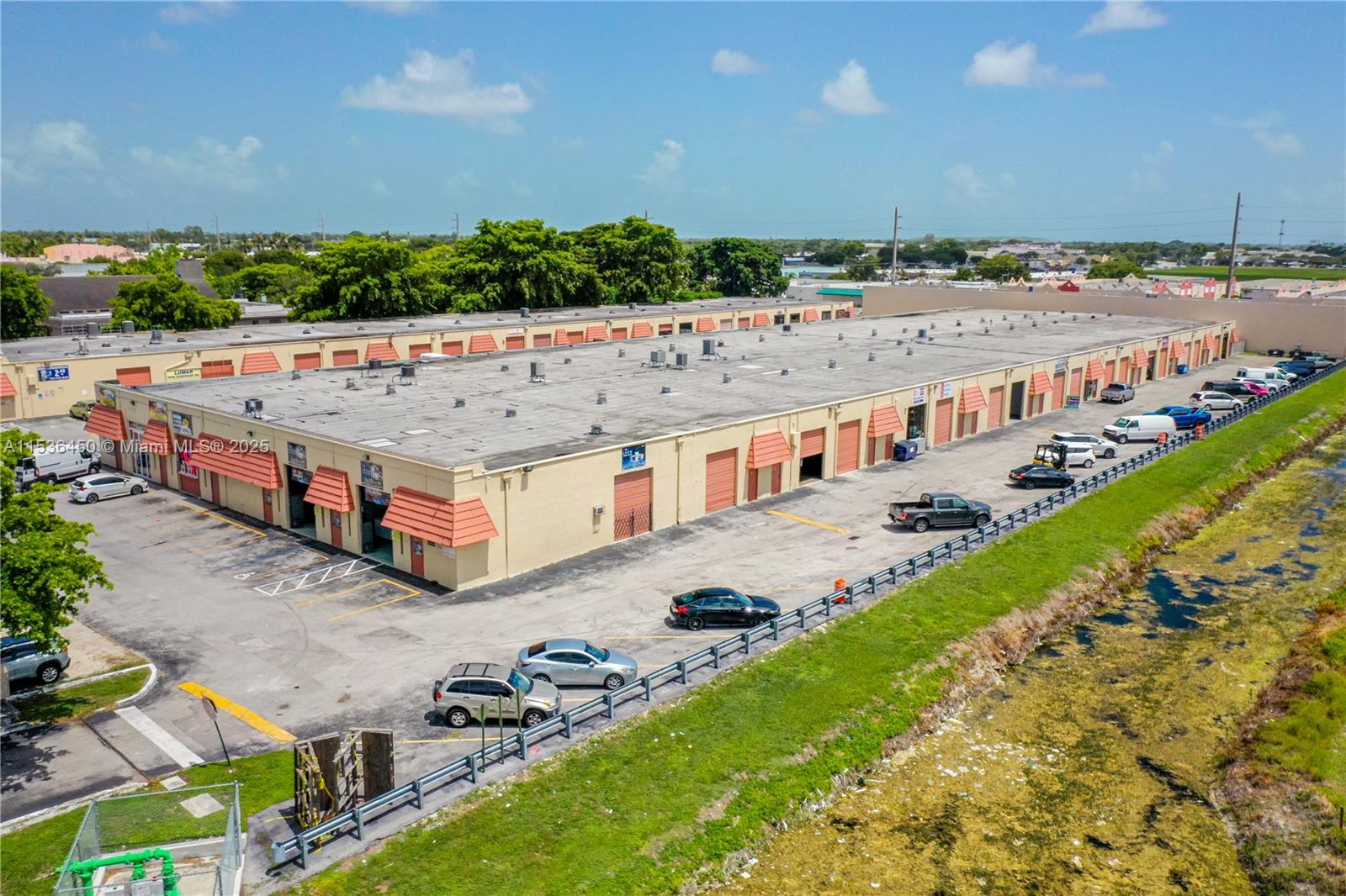 An aerial view shows a long, single-story commercial warehouse building with multiple bays and parking — 10890 QUAIL ROOST DR, Miami FL 33157, MIAMI, FL