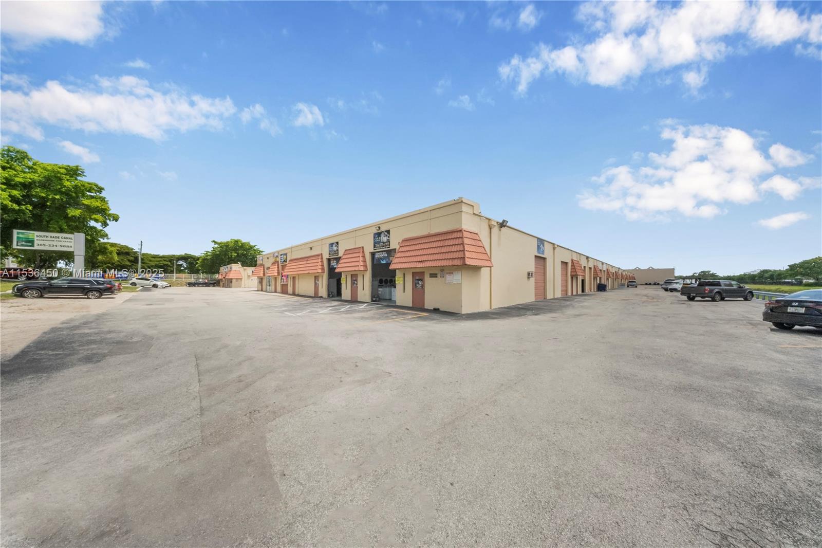 A low-rise commercial warehouse building features multiple bays with orange tile awnings and parking — 10890 QUAIL ROOST DR, Miami FL 33157, MIAMI, FL