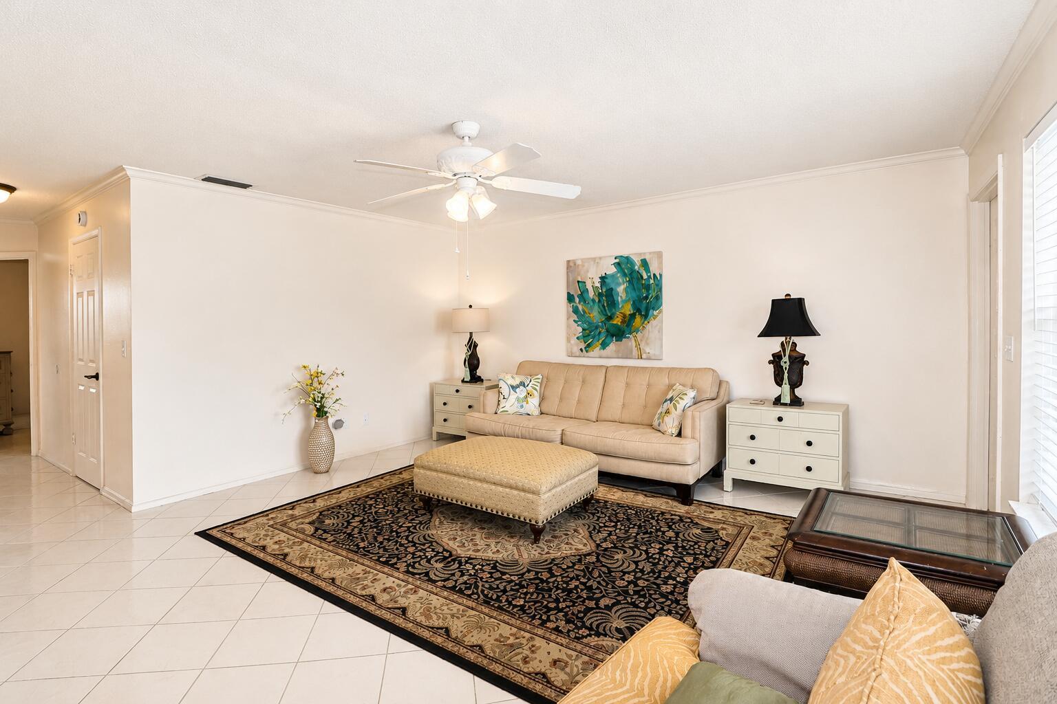 A living room features a beige sofa, a patterned area rug, and a ceiling fan — 2929 SE Ocean Boulevard # 10, Stuart FL 34996, STUART, FL