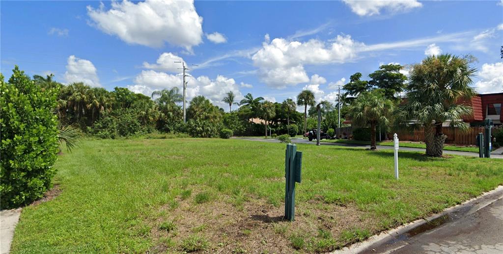 A vacant, grassy residential lot features palm trees and a utility pole under a cloudy sky — 11954 QUAIL RUN DRIVE, FORT MYERS, FL
