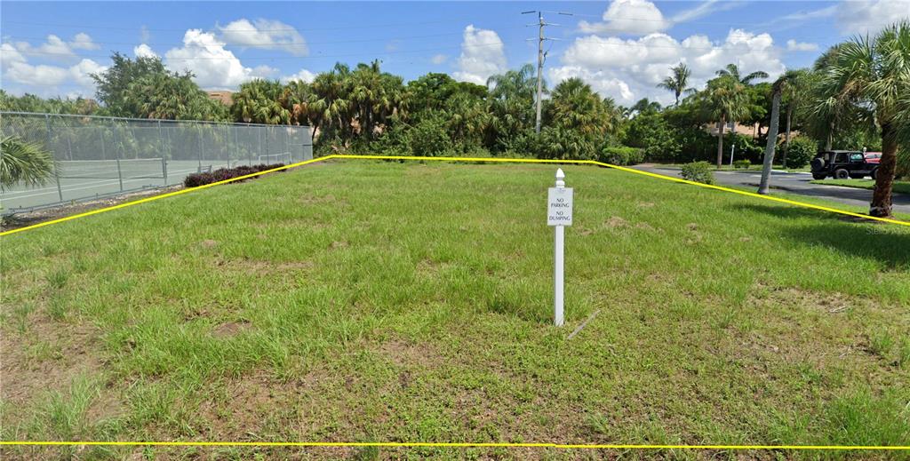 A vacant, grass-covered rectangular lot is outlined in yellow next to a tennis court — 11954 QUAIL RUN DRIVE, FORT MYERS, FL