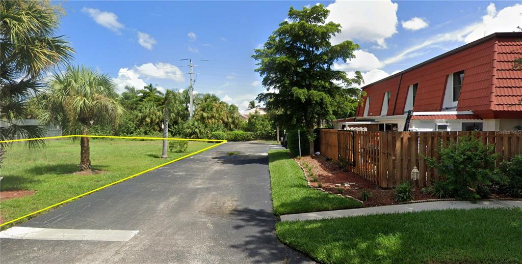 A grassy vacant lot sits next to a paved driveway and a multi-story residential building — 11954 QUAIL RUN DRIVE, FORT MYERS, FL