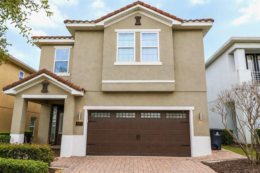 A two-story house with a brown garage door, tan stucco exterior, and a tiled roof — 640 LASSO DRIVE, KISSIMMEE, FL