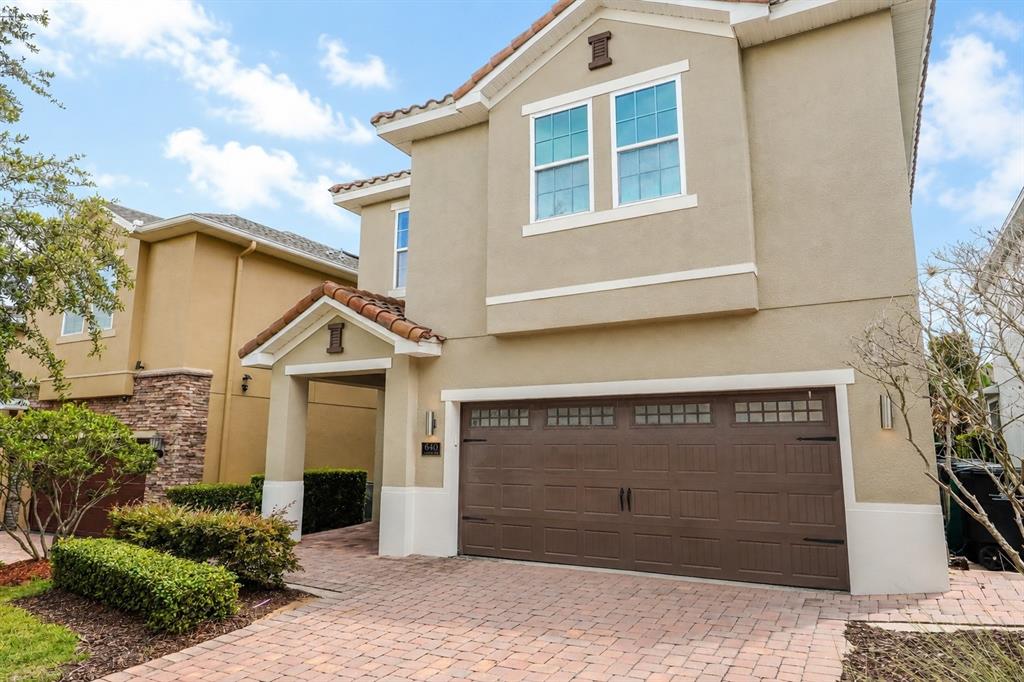 A two-story tan stucco house features a brown garage door and a paved driveway — 640 LASSO DRIVE, KISSIMMEE, FL