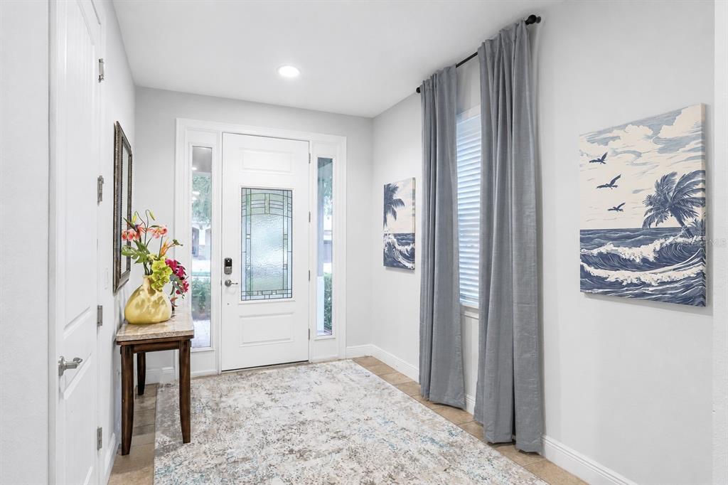 An entryway features a white front door, a console table, and coastal-themed wall art — 640 LASSO DRIVE, KISSIMMEE, FL