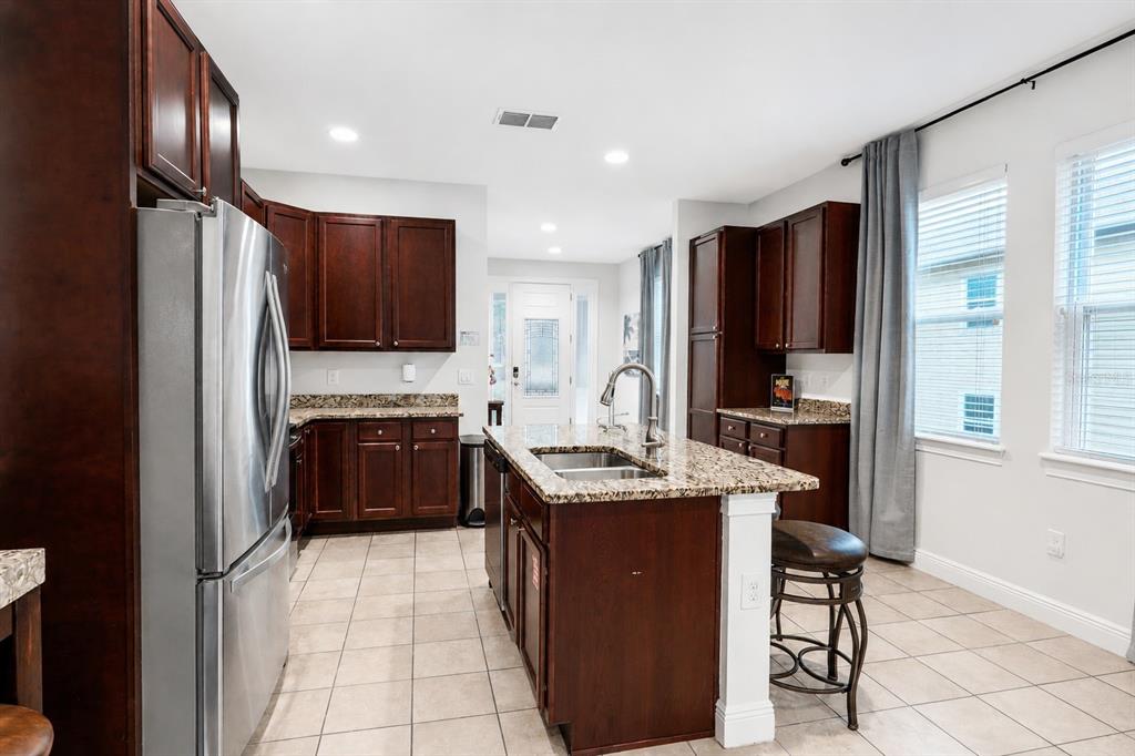 A kitchen features dark wood cabinets, granite countertops, a center island, and stainless steel appliances — 640 LASSO DRIVE, KISSIMMEE, FL