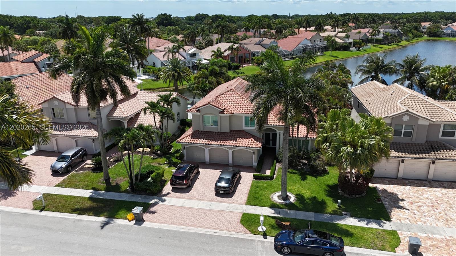 An aerial view shows suburban houses with tile roofs, palm trees, and a lake — 19432 Preserve Dr, Boca Raton FL 33498, BOCA RATON, FL