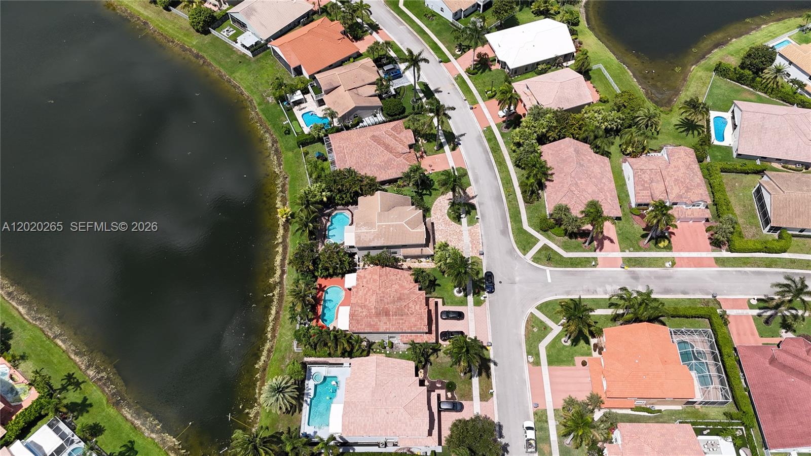 An aerial view shows several suburban houses with swimming pools situated along a lake — 19432 Preserve Dr, Boca Raton FL 33498, BOCA RATON, FL