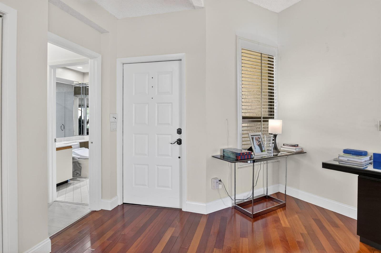 An entryway features hardwood floors, a white door, and a glass console table — 7535 La Paz Boulevard # 301, Boca Raton FL 33433, BOCA RATON, FL