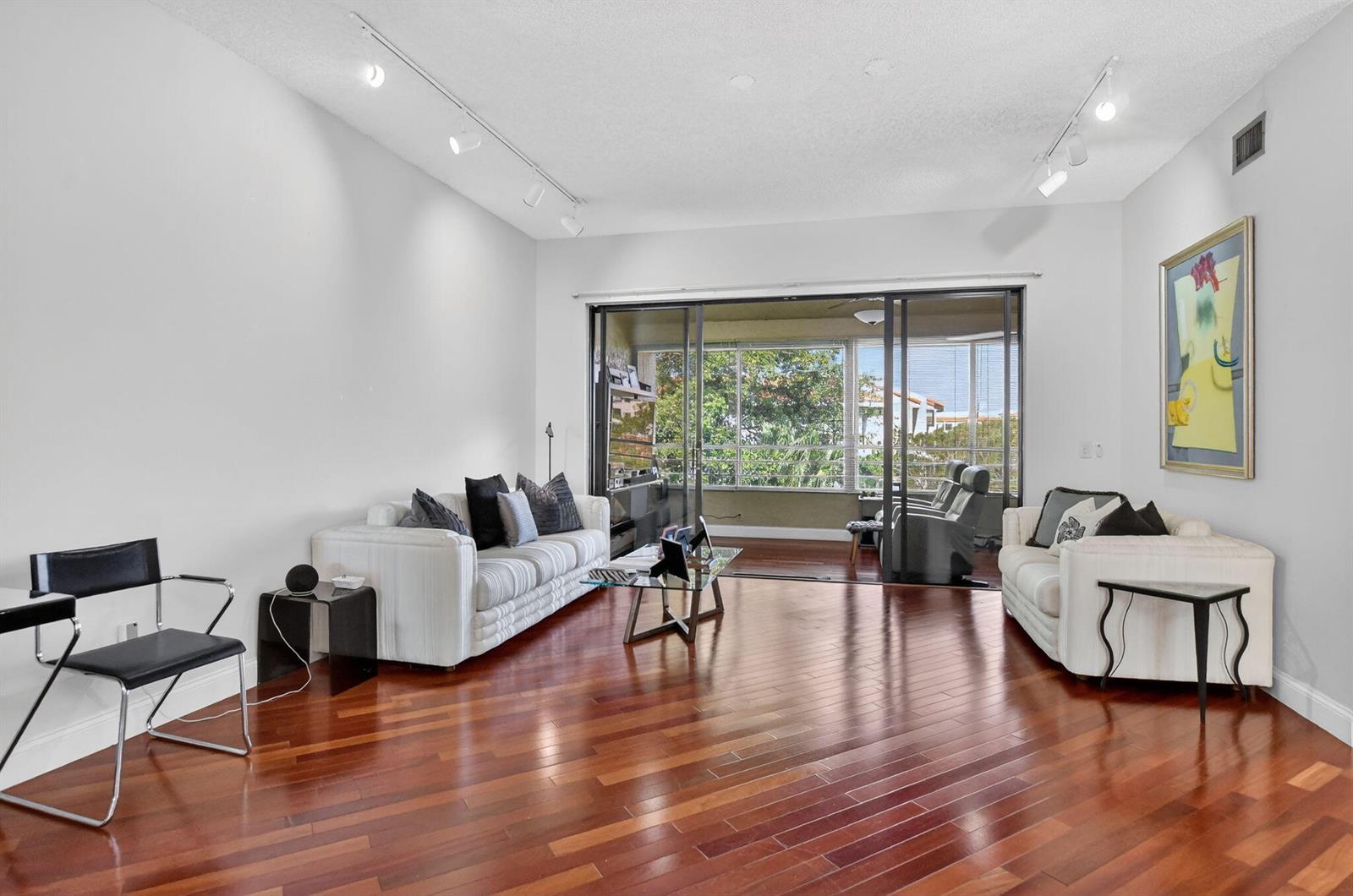 A living room with hardwood floors, two white sofas, and a sliding glass door balcony — 7535 La Paz Boulevard # 301, Boca Raton FL 33433, BOCA RATON, FL