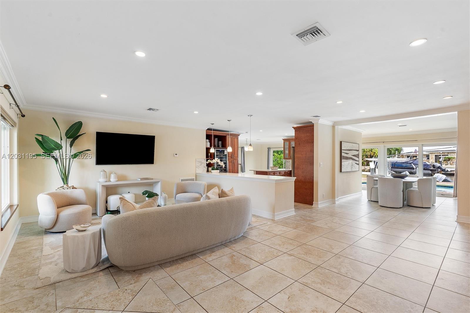 An open-concept living and dining area features tile flooring, a kitchen island, and patio views — 370 SE 12th Ave, Pompano Beach FL 33060, POMPANO BEACH, FL