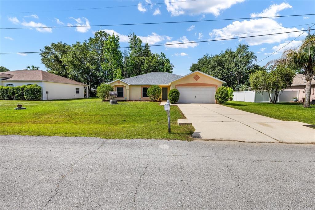 A single-story house with a beige exterior, a two-car garage, and a concrete driveway — 16 SLUMBER PATH, PALM COAST, FL