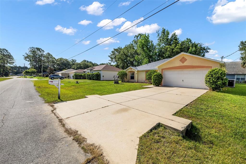 A single-story house with a two-car garage and a concrete driveway sits on a lawn — 16 SLUMBER PATH, PALM COAST, FL