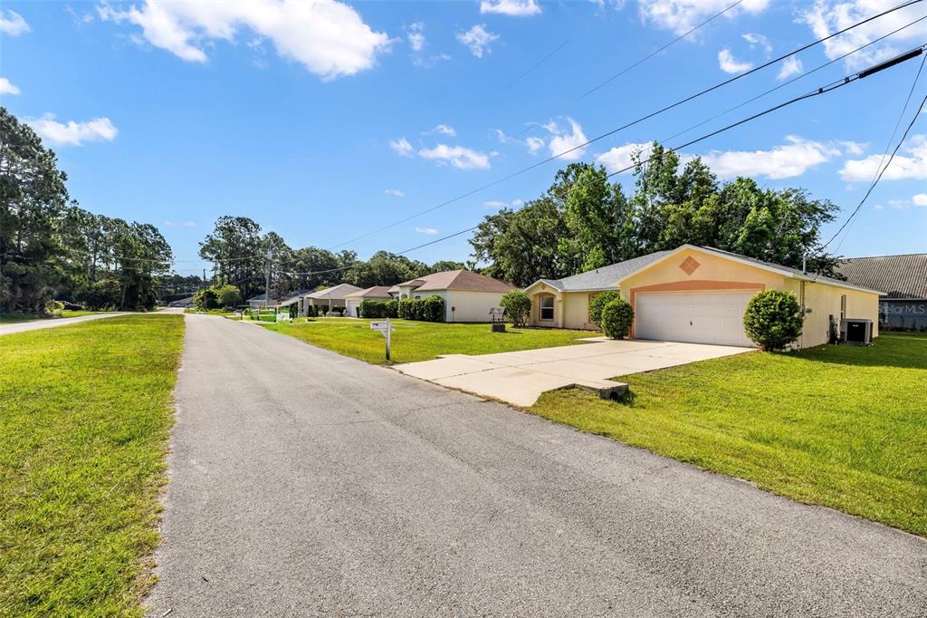 A single-story house with a two-car garage sits along a paved residential street — 16 SLUMBER PATH, PALM COAST, FL