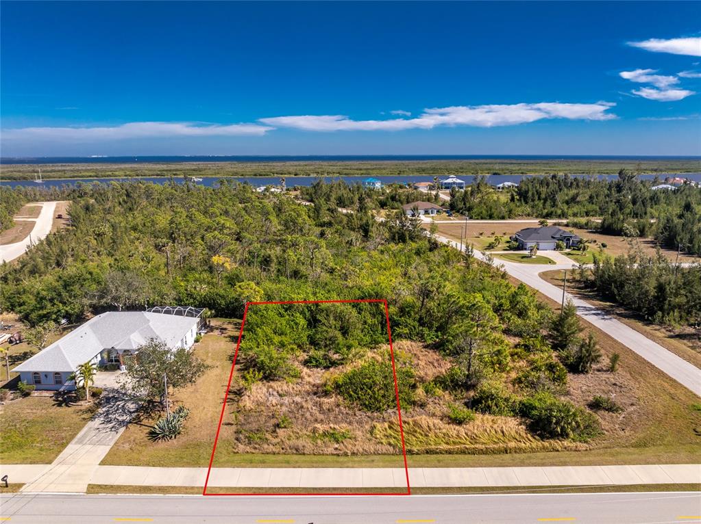 An aerial view shows a vacant, rectangular residential lot outlined in red along a road — 9346 ST PAUL DRIVE, PORT CHARLOTTE, FL
