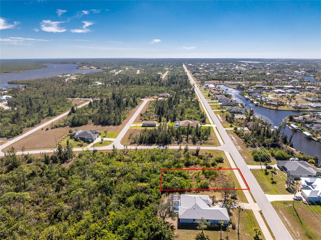 An aerial view shows a vacant rectangular lot outlined in red next to a house — 9346 ST PAUL DRIVE, PORT CHARLOTTE, FL