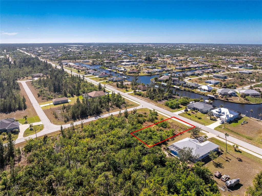 An aerial view shows a vacant, rectangular lot outlined in red within a residential neighborhood — 9346 ST PAUL DRIVE, PORT CHARLOTTE, FL