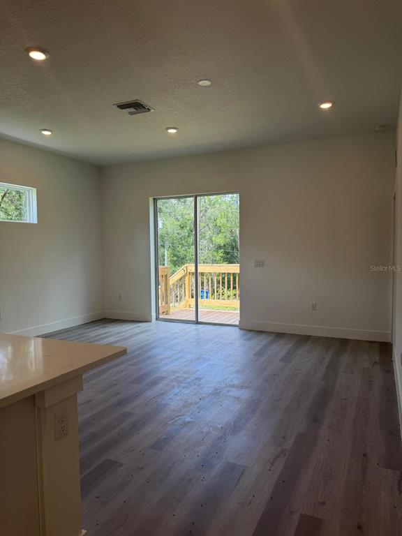 An interior view of a living room with light wood-look flooring and a sliding glass door — 11183 N VESTA POINT, CITRUS SPRINGS, FL